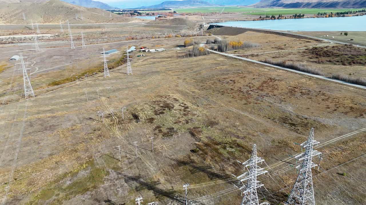 Drone captures expansive view of power lines and substation in New Zealand's rugged landscape under clear skies