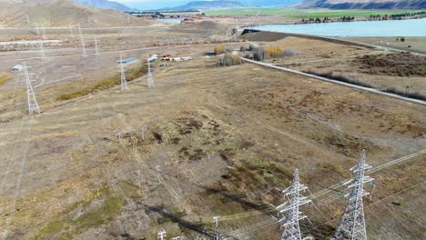 drone captures expansive view of power lines and substation in new zealand's rugged landscape under clear skies