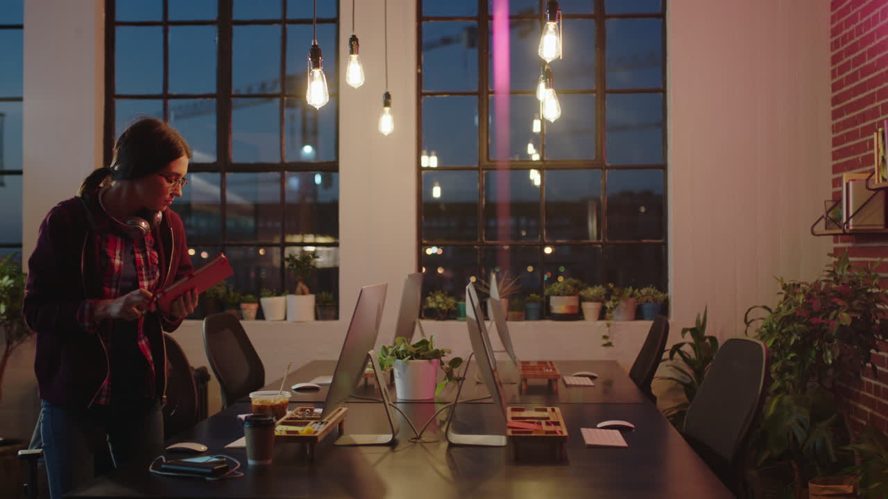 joven mujer de negocios caucásica que trabaja hasta tarde dejando la oficina terminó con éxito la fecha límite del proyecto en el lugar de trabajo moderno por la noche