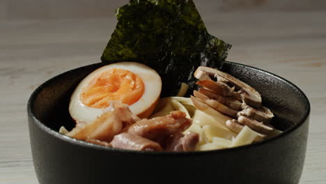 woman adding seaweed to a bowl of ramen