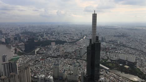 Supertall-skyscraper-in-Ho-Chi-Minh-City,-drone-orbit-at-top-with-city-view