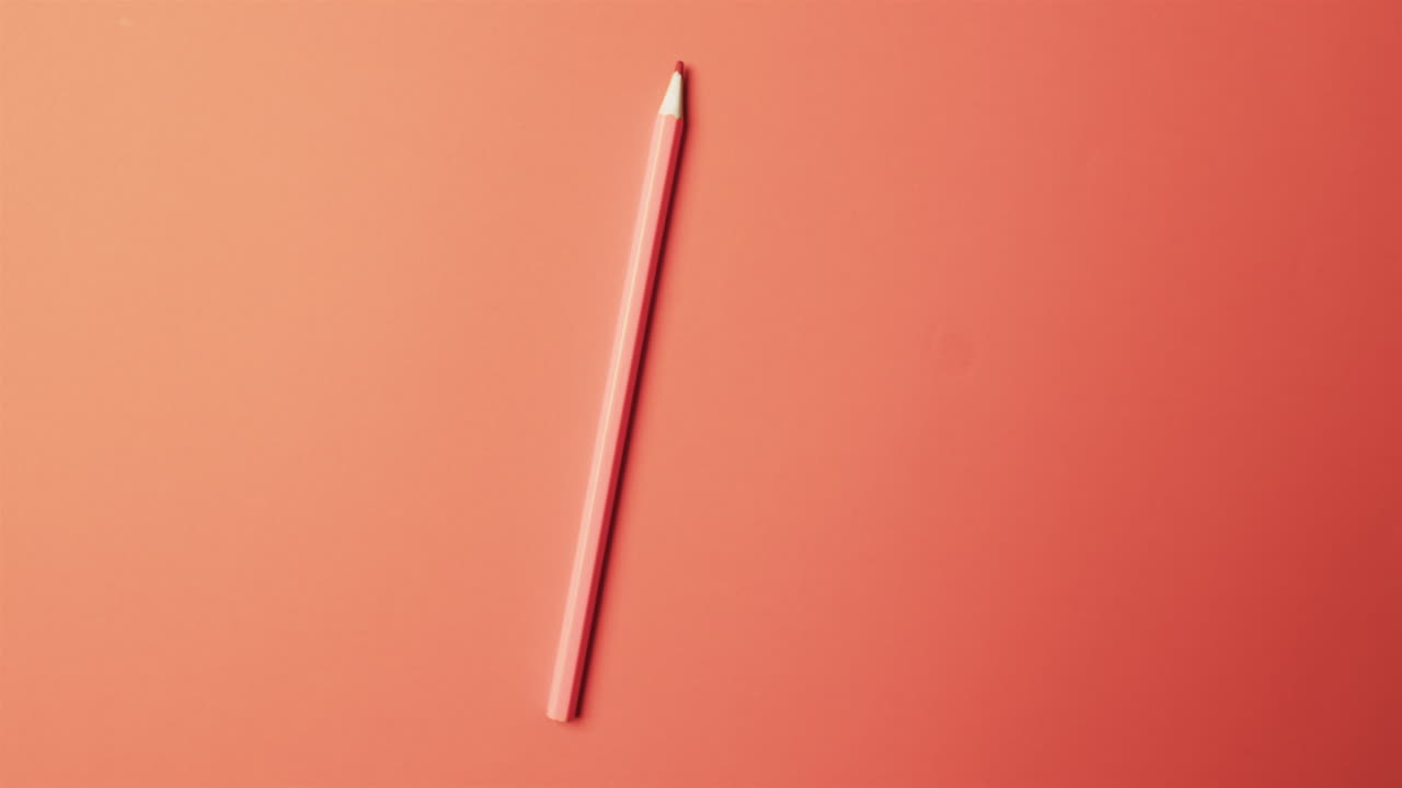 vista aérea de un lápiz rojo con espacio de copia en fondo rojo, en cámara lenta