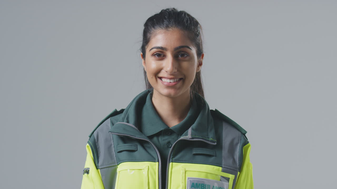 retrato de estudio de una joven paramédica sonriente contra un fondo plano