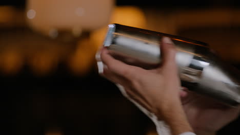 closeup shot of a bartender shaking a cocktail in a cocktail shaker