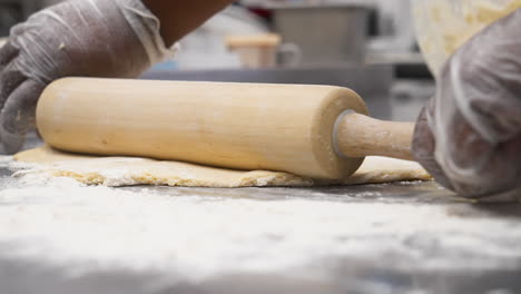 African-American-baker-rolls-outpastry-dough-with-rolling-pin,-slow-motion-close-up-4K