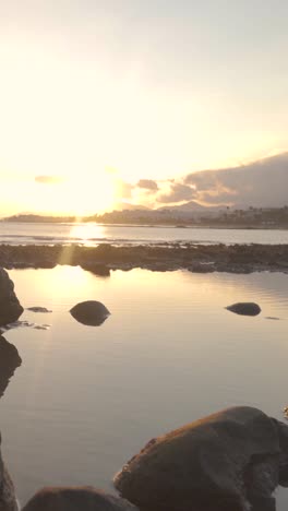 sunset over the calm ocean and rocks at the seashore