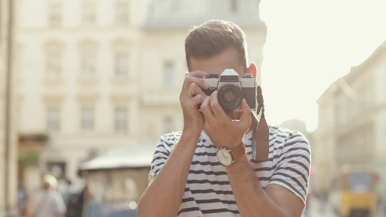 retrato de un apuesto fotógrafo masculino parado en el casco antiguo, tomando una foto y luego sonriendo a la cámara