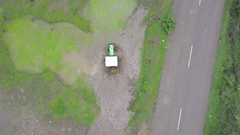 an agricultural tractor on the mud off the road in trimbakeshwar, india after the monsoon - aerial top view