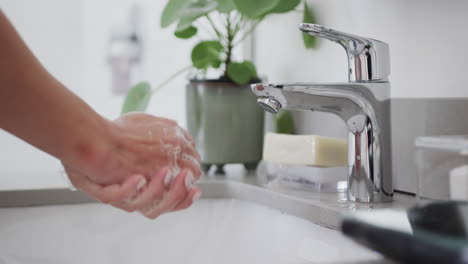 close up of biracial woman washing hands in bathroom, slow motion