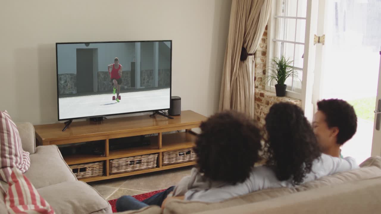 Famiglia felice seduta a casa insieme che guarda la corsa di atletica in TV