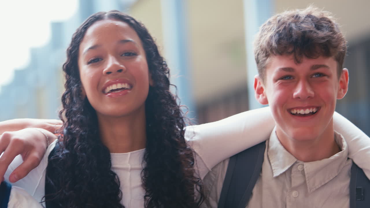 Close Up Portrait Of Smiling Multi-Cultural High School Or Secondary Pupils Sitting On Wall Outdoors