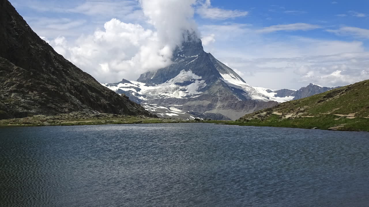 Filmato in timelapse di nuvole in rapido movimento intorno alla cima del Cervino sopra il lago Riffelsee a Zermatt, Vallese, Svizzera, con paesaggio alpino e acqua limpida.