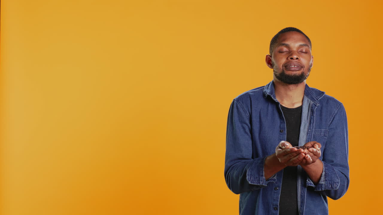 Coffee enthusiast looks at aromatic roasted beans against orange background