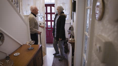 an elderly man and a visitor in a home entryway