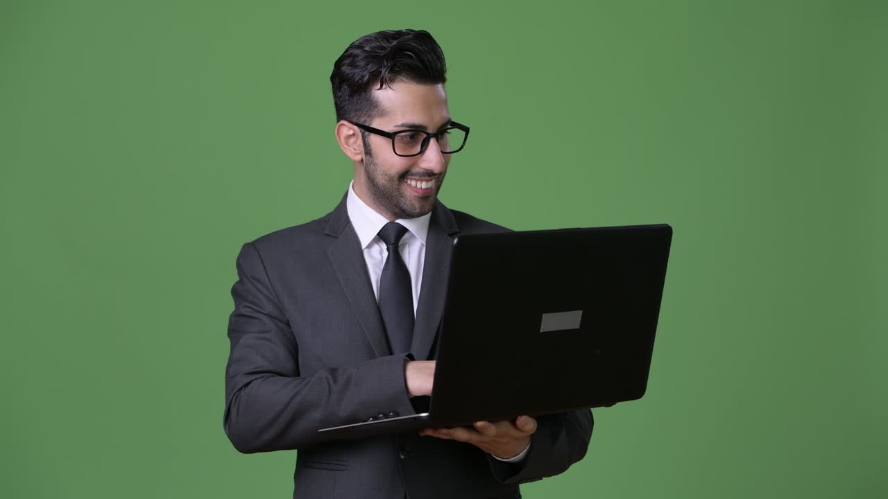 joven empresario persa barbudo y guapo contra un fondo verde