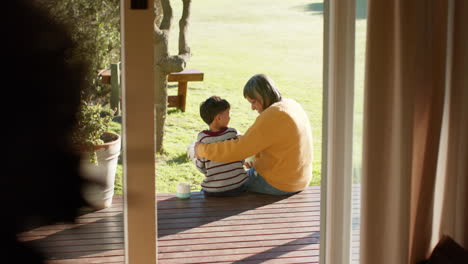 Feliz-Abuela-Birracial-Y-Nieto-Abrazándose-Sentados-En-La-Terraza,-Cámara-Lenta