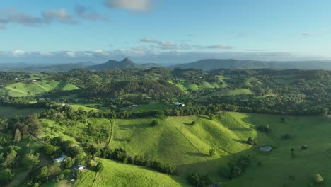 Drone-flying-over-hills-near-Cooroy-Noosa,-QLD,-with-hilly-terrain-and-the-Glass-House-Mountains-in-the-background