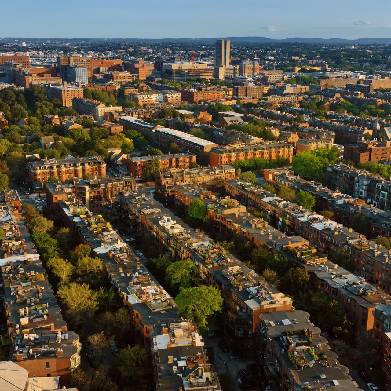 View of sunlit facades of old multistoried buildings of Boston, Massachusetts, USA. Cityscape full of greenery from aerial view