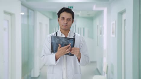 sad indian doctor explaining x ray report to patient