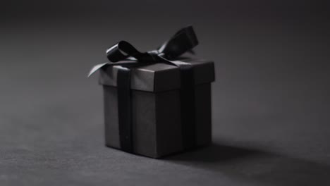 black gift box with black ribbon on dark grey background with copy space