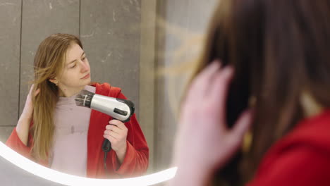 mujer secándose el cabello frente a un espejo