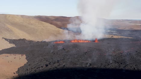 Meradalir-valley-fissure-volcano-eruption-spewing-molten-lava-and-smoke,-sunny-day,-aerial