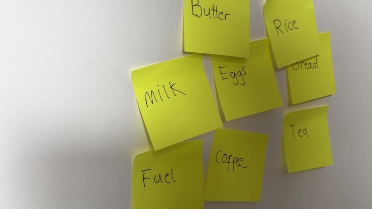 Groceries Sticky Note on Wall with Other Household Expense Reminders