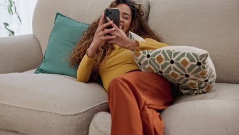 woman sitting on couch and using phone