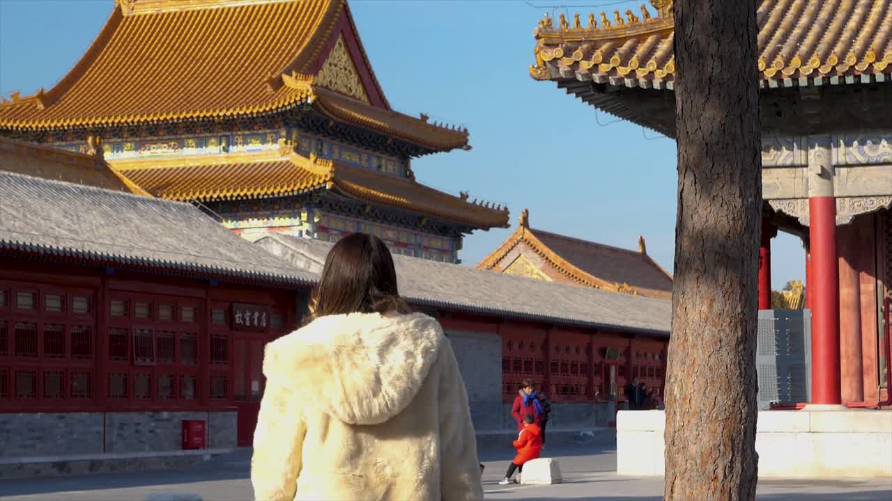 A girl walks through a beautiful Chinese temple in Beijing, surrounded by serene winter scenery, while the rich architecture adds to the tranquil atmosphere.