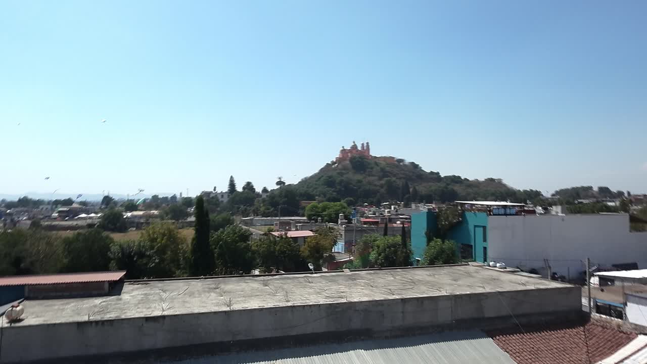 Vista della Piramide di Cholula dai tetti della città sotto un cielo azzurro limpido