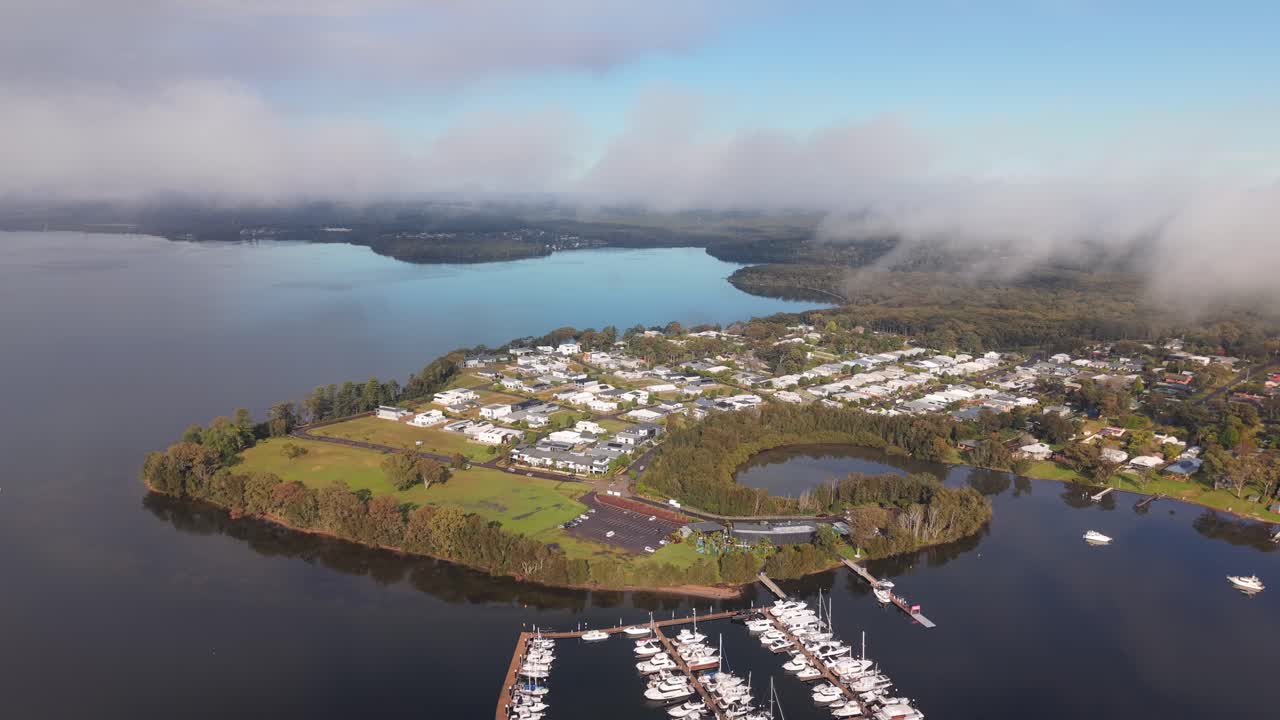 Trinity Point waterfront homes and marina viewed from above in clear conditions, aerial pullback