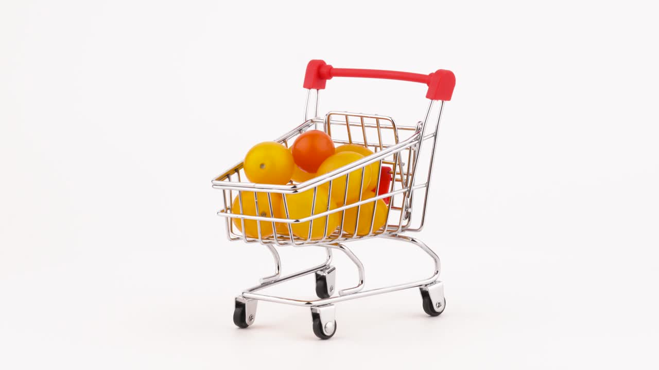 노란색 체리 토마토 어리로 가득 찬 슈퍼마켓 트롤리, 회전 테이블에서 회전, 색 배경에서 고립, 클로즈업, 매크로.