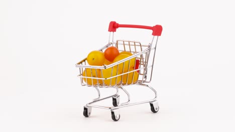 el carrito del supermercado está lleno de tomates de cereza amarillos. rotando en la mesa giratoria. aislado en el fondo blanco. primer plano. macro.