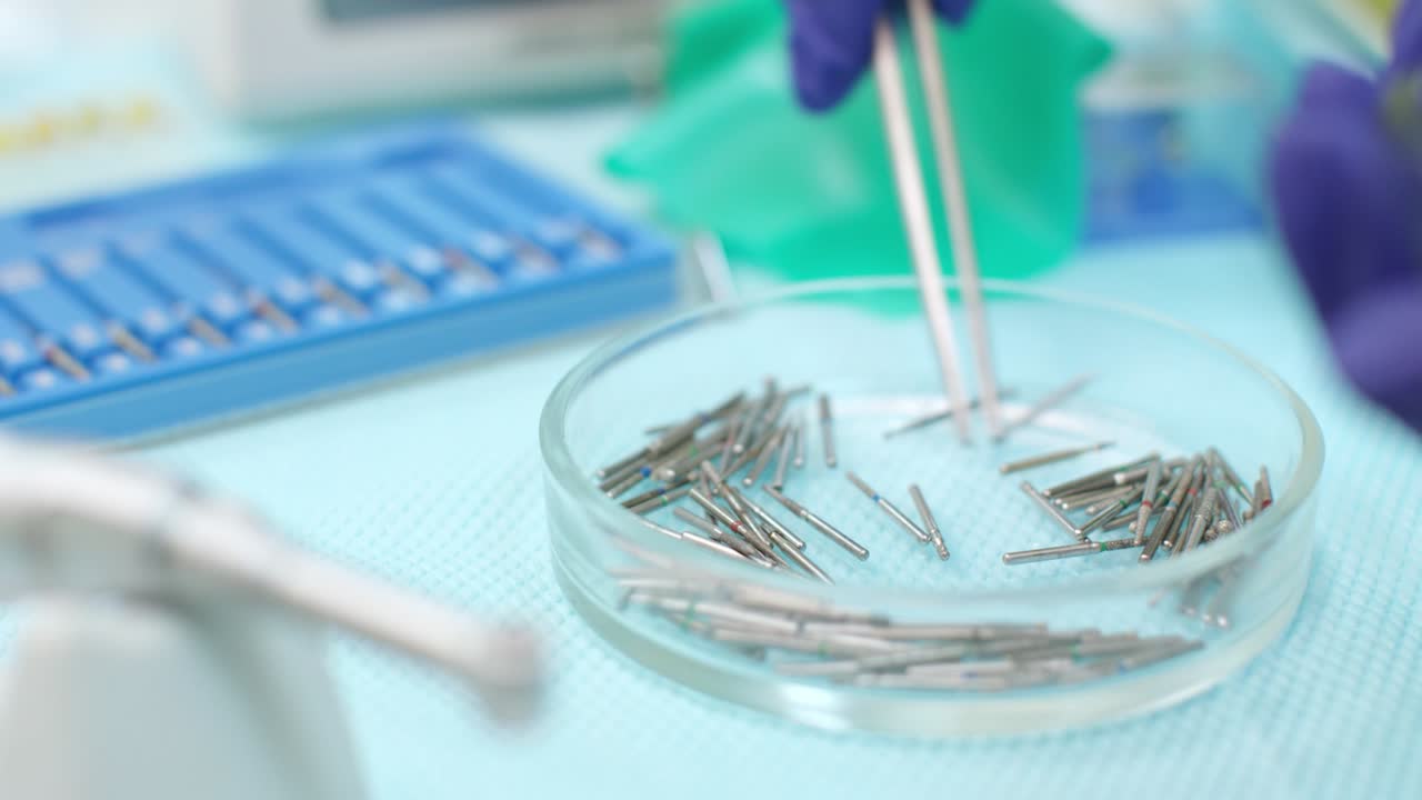 mano de estomatólogo con guantes de látex con pinzas médicas. perforaciones dentales