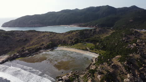 Aerial-view-of-vietnamese-bay-with-mountains-and-coastline-during-sunny-day---Beautiful-drone-panorama-shot-of-reflecting-water-and-bright-sky