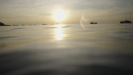 sun's golden reflection on calm ocean water with distant boats