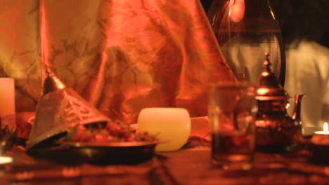 romantic scene candle lit of a moroccan theme foreground with soft-focus sliding to reveal the back of a lady getting undress in the background