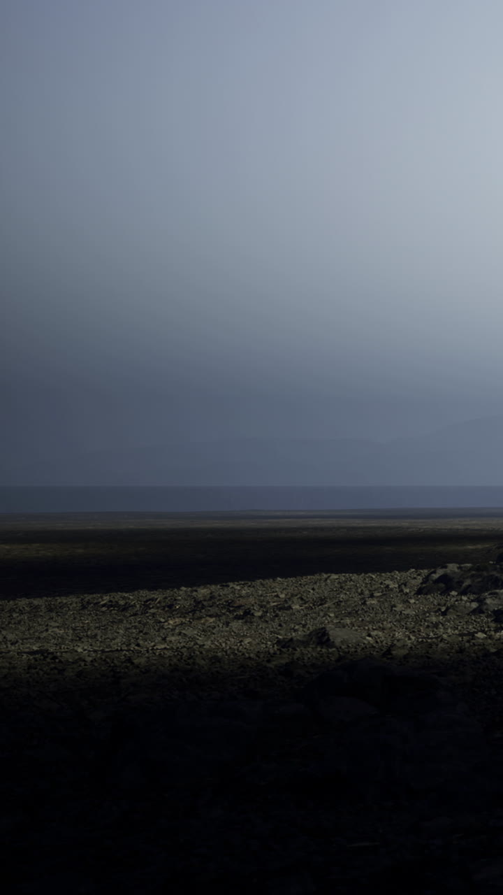 Wide landscape view of dark earth under cloudy sky at dusk