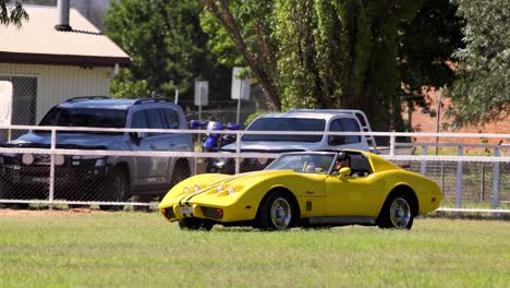 vintage yellow car driving by a fence