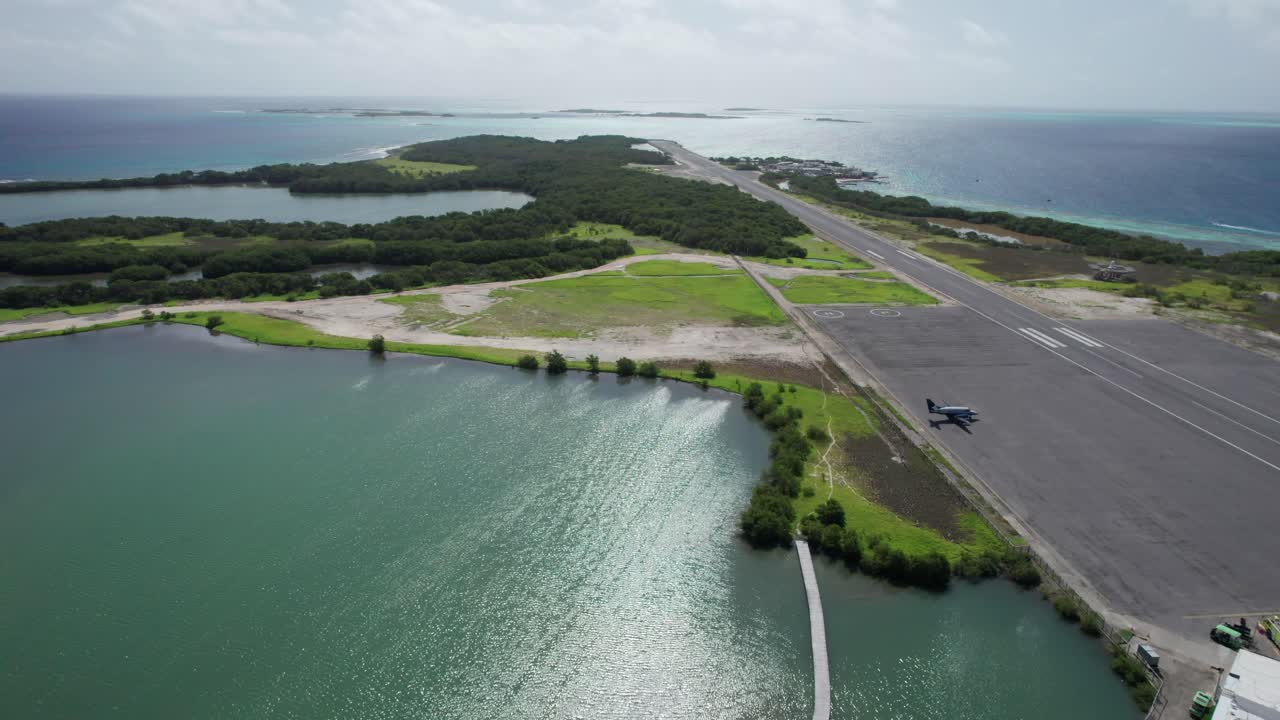 Backward aerial view over Los Roques runway and ocean on a cloudy day