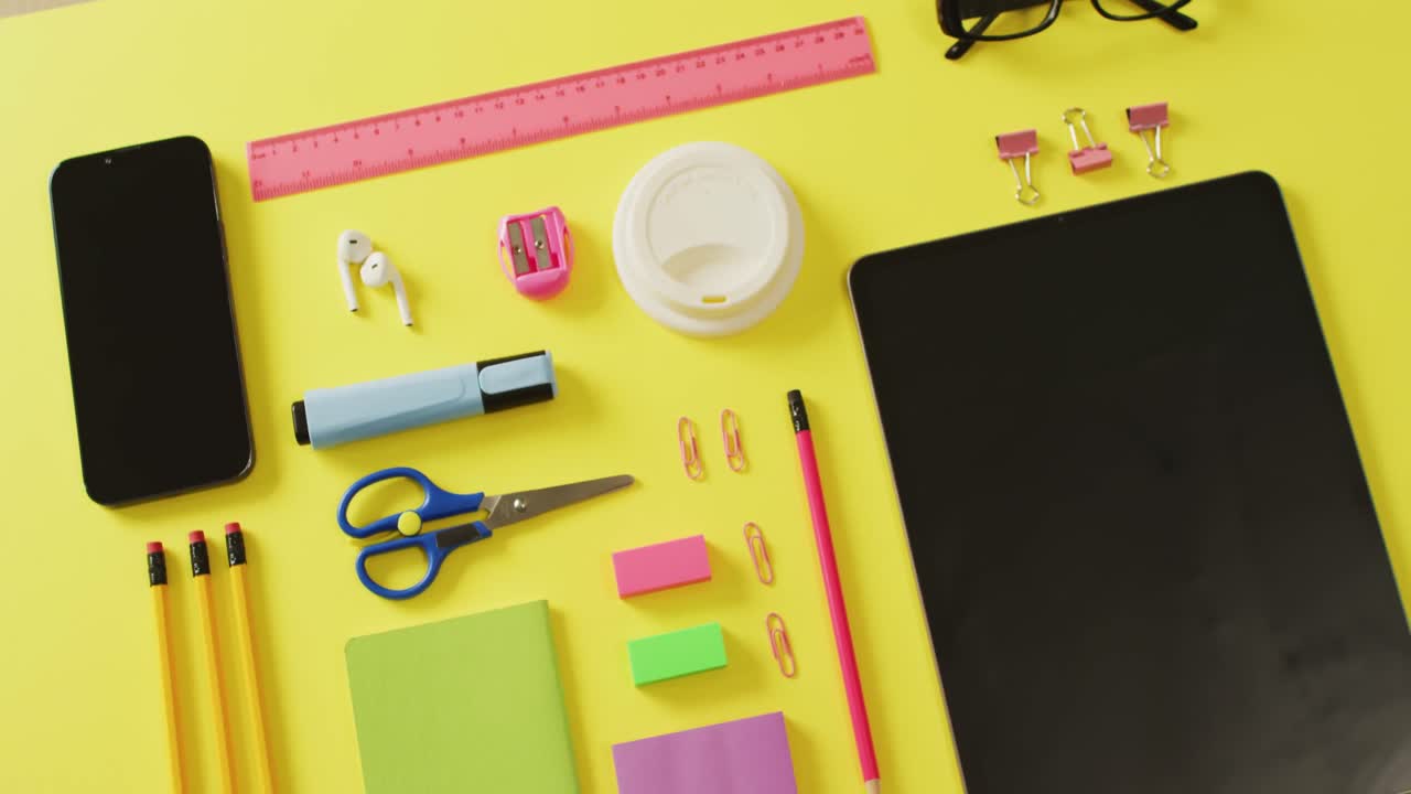 노란색 배경에 복사 공간을 가진 다양한 사무실 도구, 태블릿 및 스마트 폰의 비디오