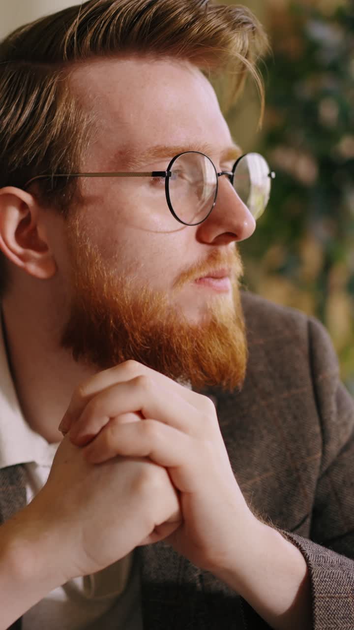 Thoughtful Man with Red Beard and Glasses Pondering Indoors