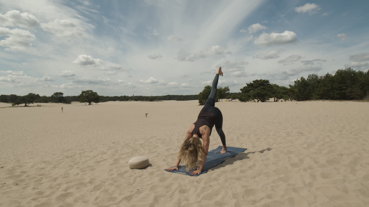 Donna solleva la gamba destra mentre esegue la posizione yoga del cane a testa in giù
