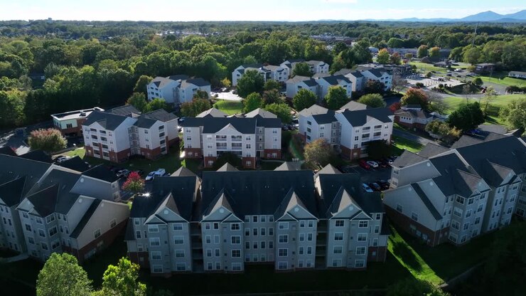 Luftaufnahme einer amerikanischen Vorstadtsiedlung mit Reihenhäusern, Mehrfamilienhäusern und Apartmentgebäuden bei Sonnenuntergang. Friedlicher Abend im Herbst. Grüne Bäume in den USA