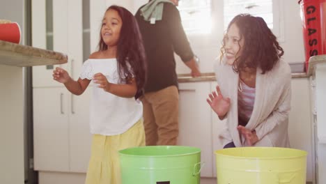 padres hispanos y hija enseñando a segregar basura plástica