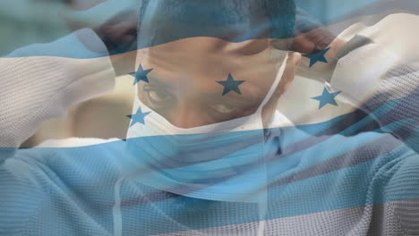 animation of flag of honduras waving over african american man wearing face mask in city street