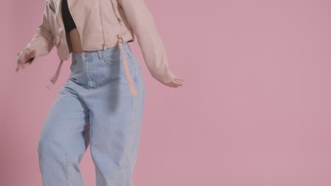 close up on legs of woman having fun dancing against pink studio background