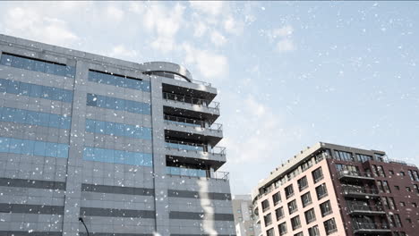 snowfall animation over modern office buildings against blue sky