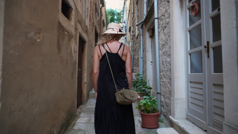 beautiful woman in dress walking on narrow street of ancient town - tracking