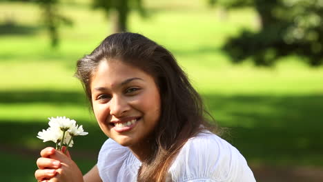 Pretty-girl-sitting-on-the-grass-smelling-flowers